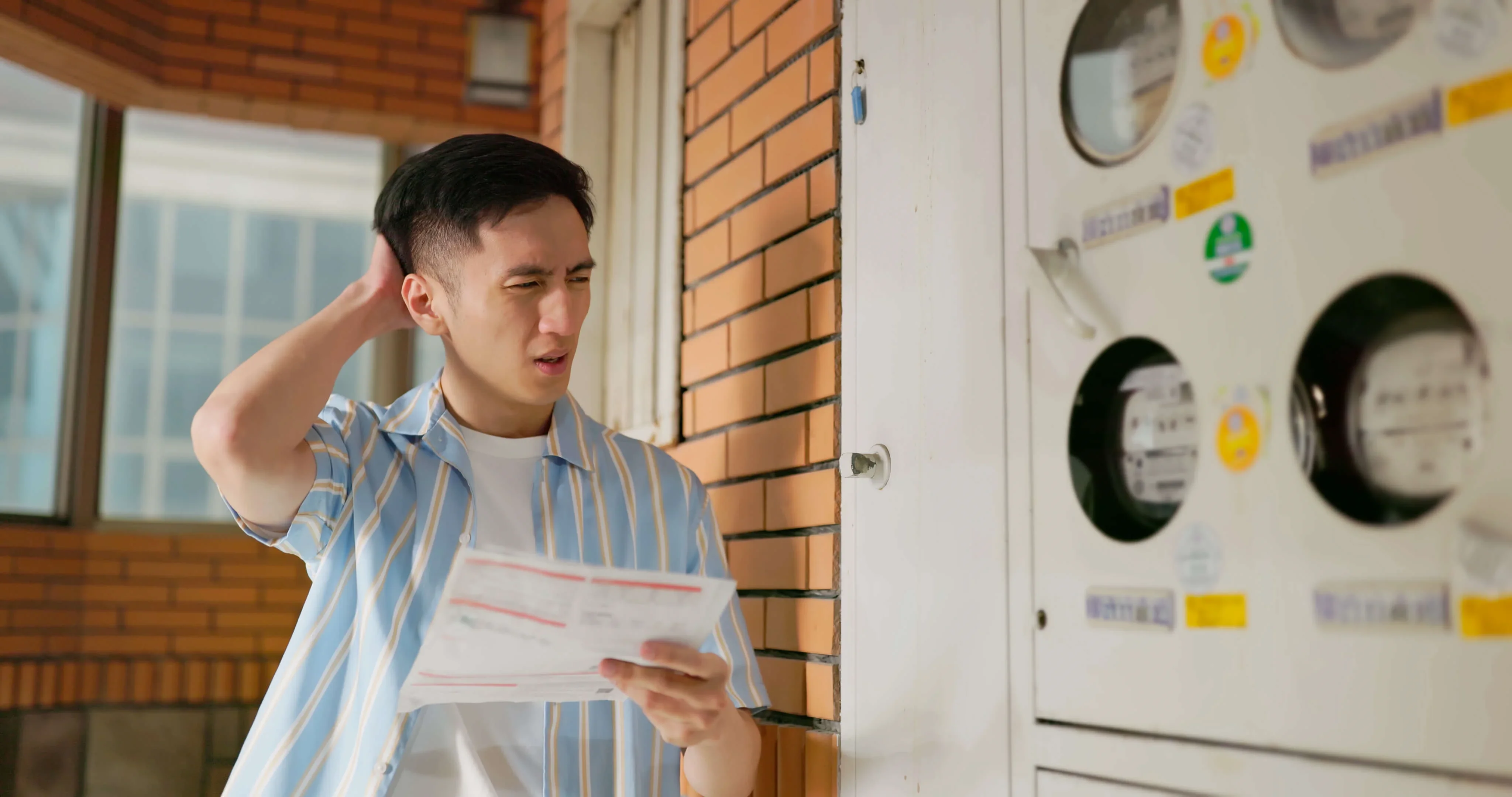 A man holding a paper and looking at his electricity meter
